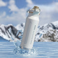 Stainless steel water bottle with ice cubes and promotional text on a snowy background